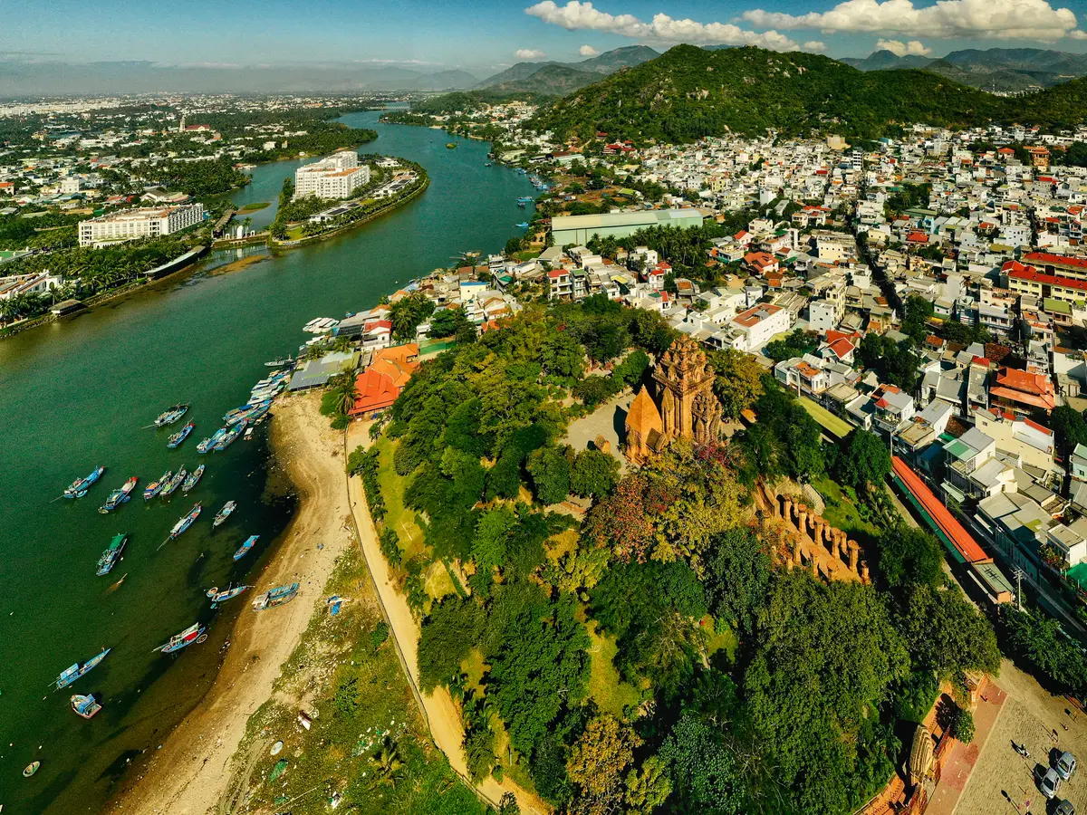 Aerial view of the river mouth with fishing boats and the wooded hill carrying the towers