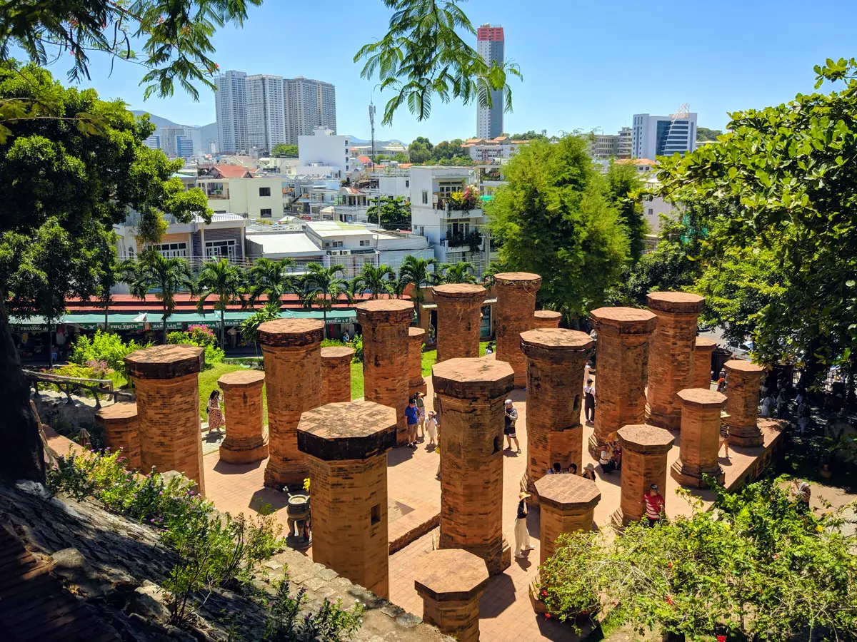 Ring of tall brick pillars of the mandapa in front of the hill with city rooftops behind