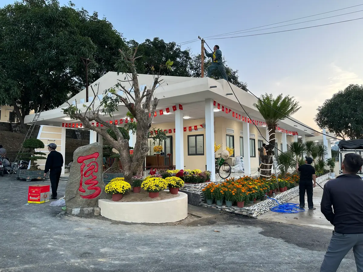 Low white office building with a covered entrance, a stone sign and flower beds in the yard.