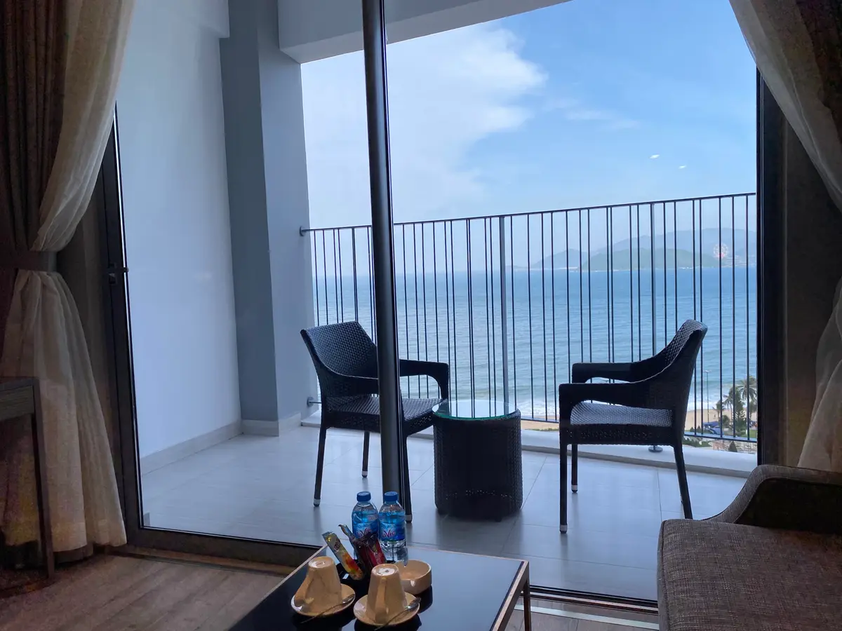Room with a curtain, a sofa and two chairs on a balcony facing the sea