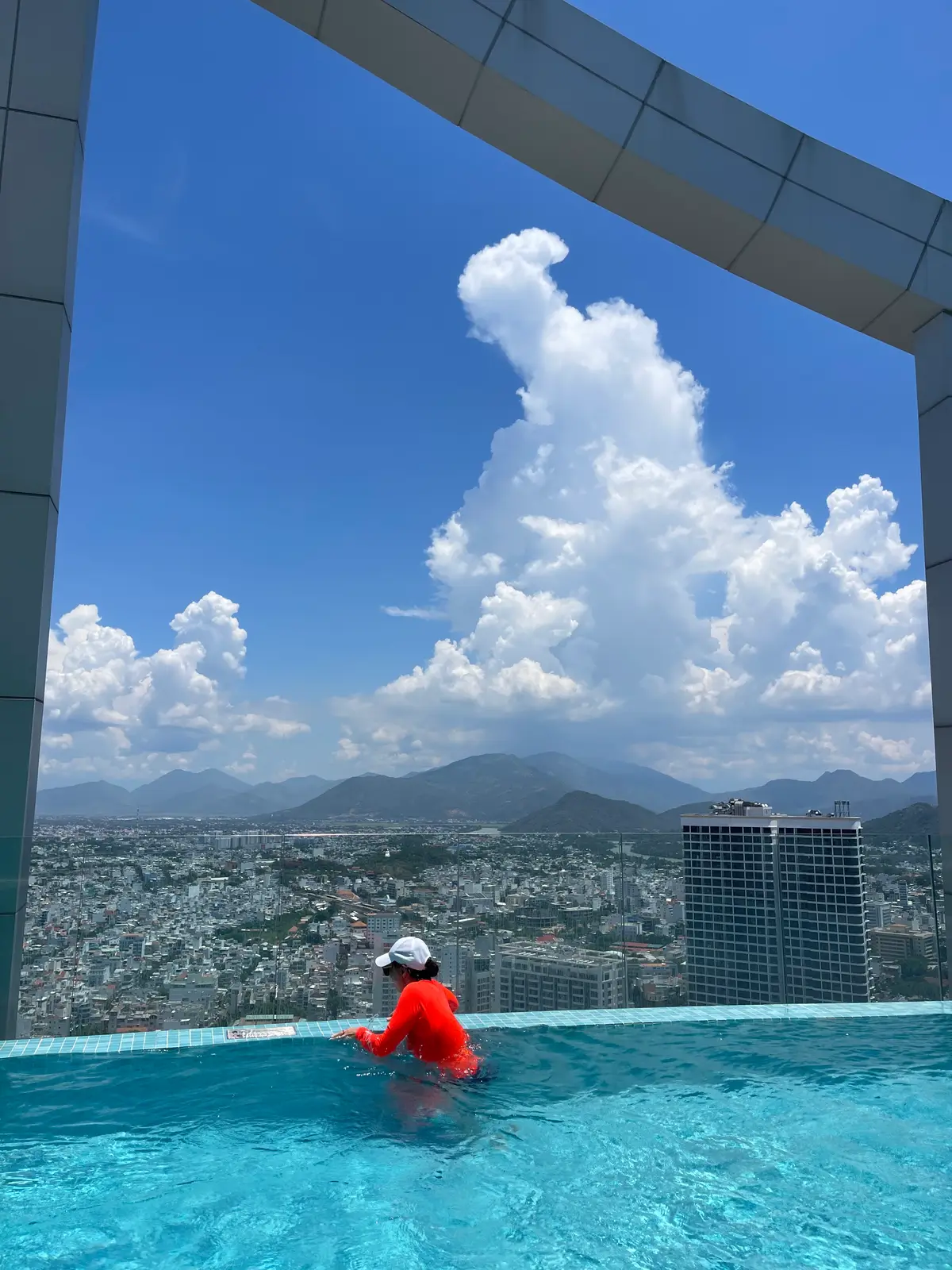 Blue sky with large clouds over mountains and the rooftops of Nha Trang seen from a high floor