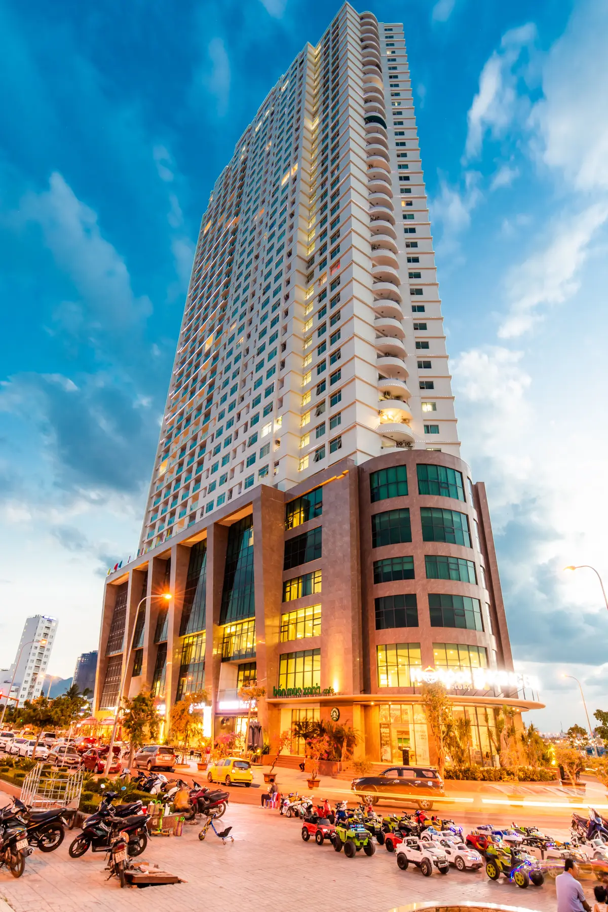 Tall tower with glass and golden balconies photographed from below against a blue sky with clouds