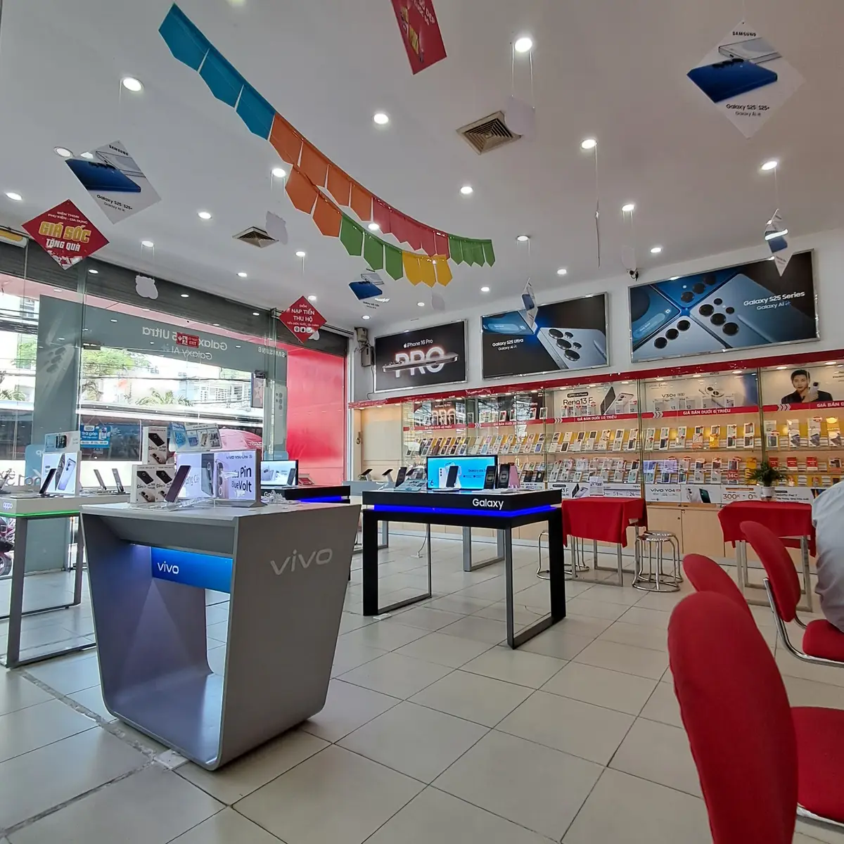 Inside a Viettel Store with phone display tables, glass shelves of accessories and red stools