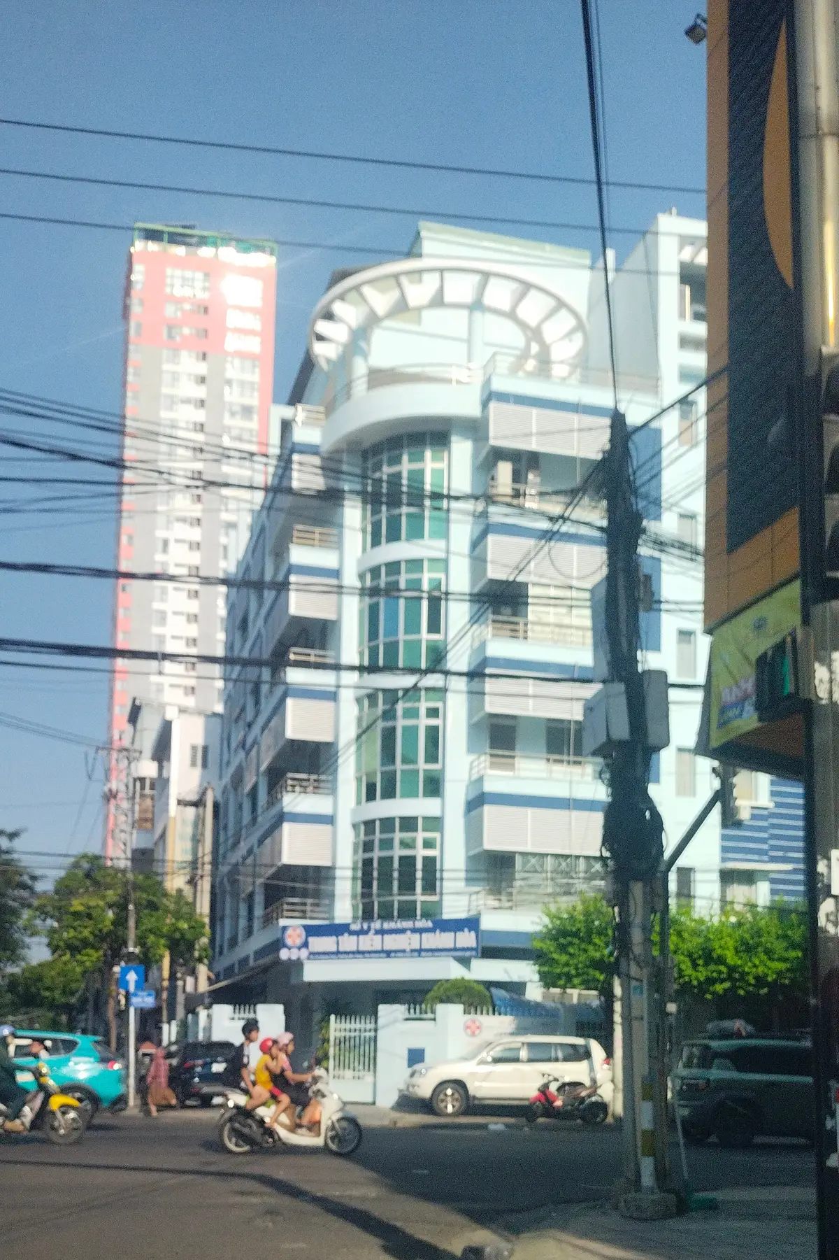 A light multi-storey building with curved balconies against a blue sky.