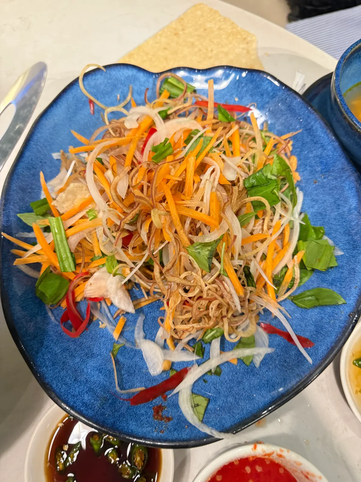 Blue plate piled with shredded carrot, onion and herbs