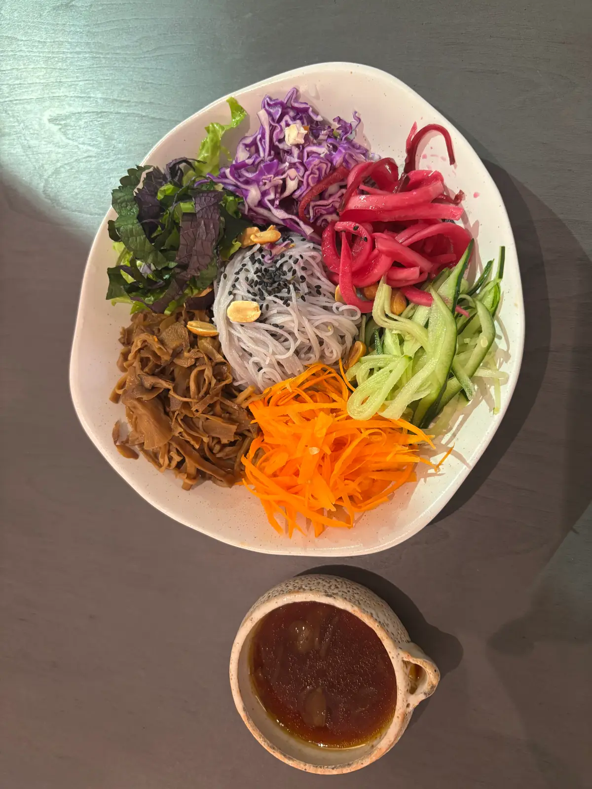 Large bowl of rice noodles with carrot, cucumber, pickled onion and mushrooms