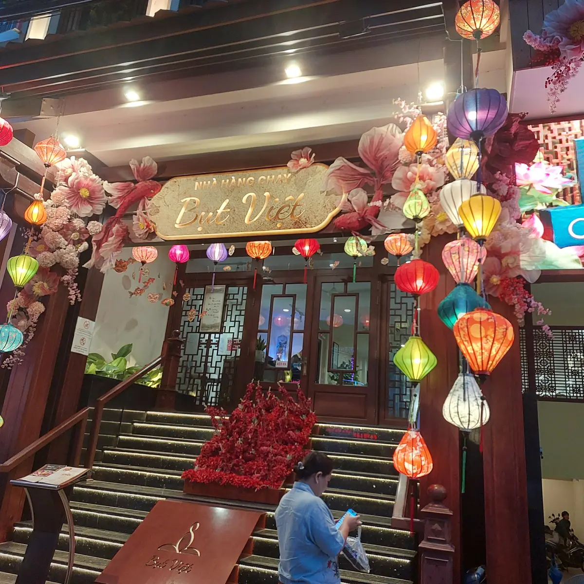 Restaurant entrance with steps, red flowers and many coloured lanterns hanging overhead