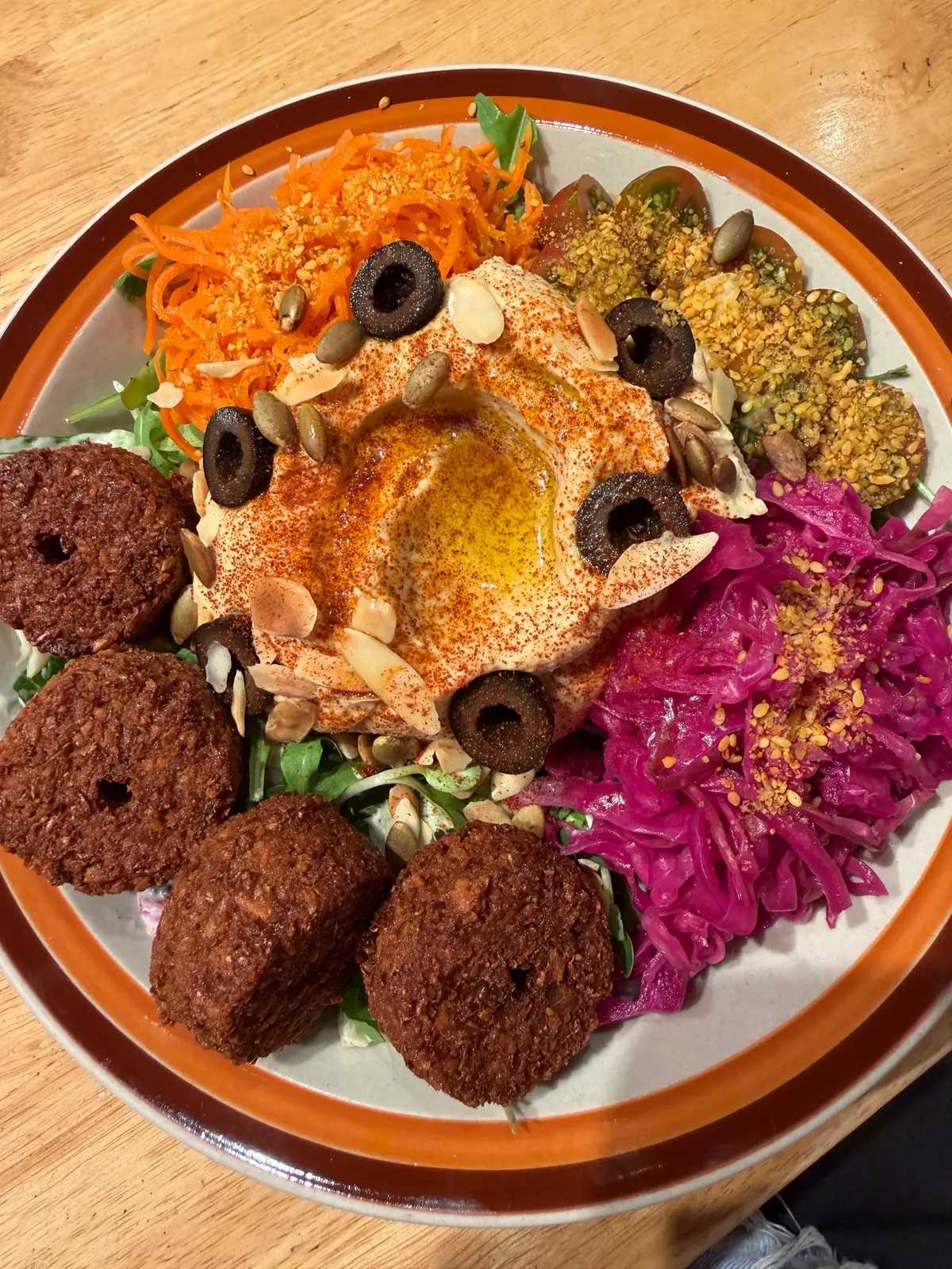 Plate of falafel with hummus, pickled red cabbage and olives