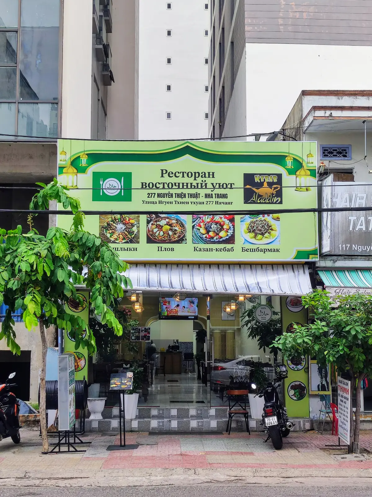 Green shop sign in Russian with food photos above a glass shopfront