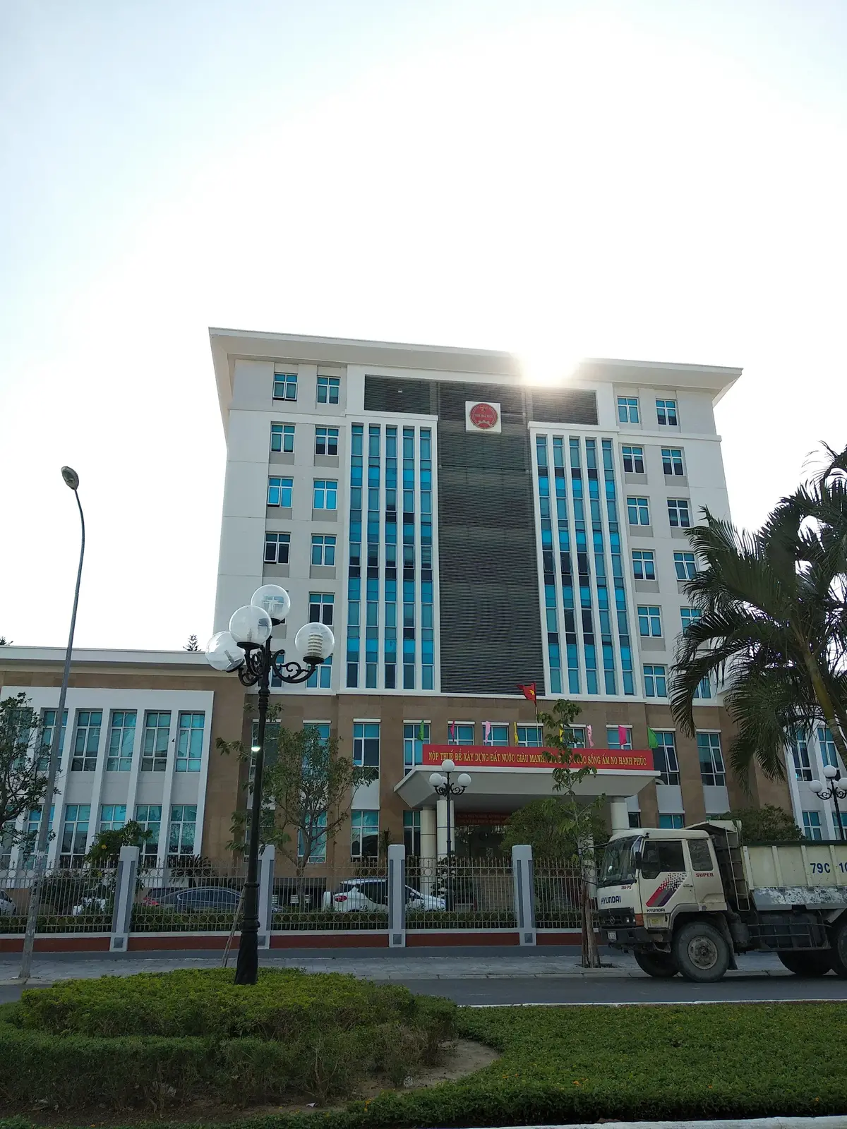Multi-storey office building with a glass front and an entrance canopy, seen from the street with a lamp post in front.