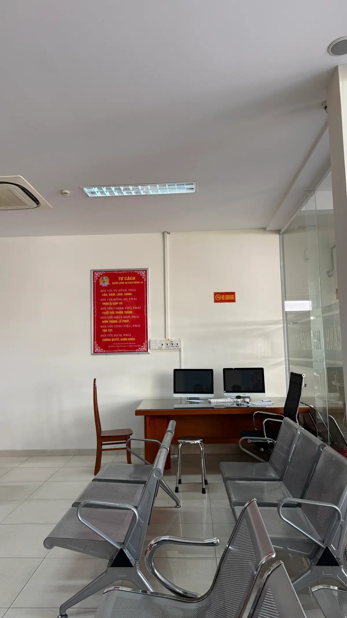 Small room inside the office with a wooden desk, two computer monitors, an office chair and a red notice board on the wall
