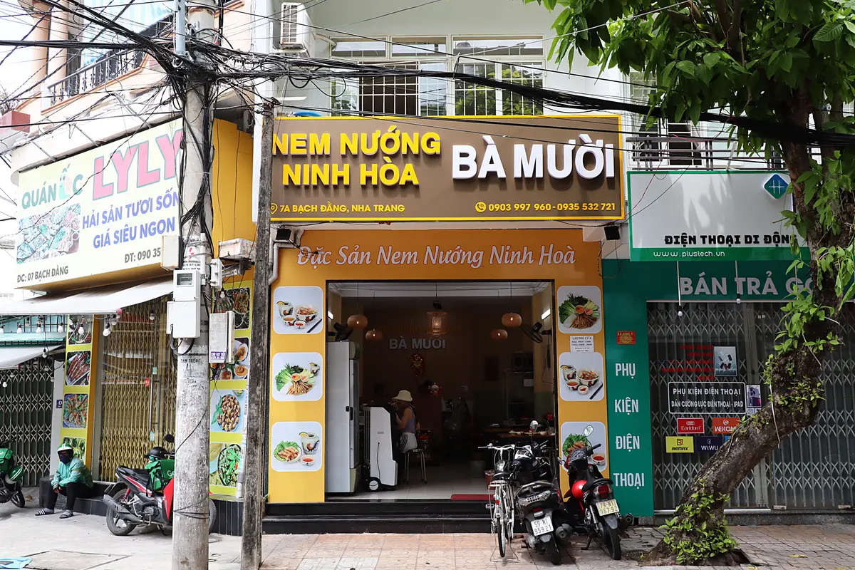 Yellow shopfront with a brown sign reading nem nuong Ninh Hoa Ba Muoi